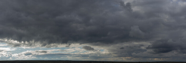 Wall Mural - Storm clouds cover the landscape. Tragic gloomy sky. Panorama. Village in the steppe. Fantastic skies on the planet earth.