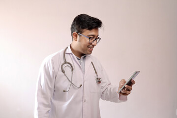 male indian doctor in white coat and stethoscope touching smart phone