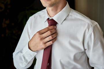 man in shirt dressing up and adjusting tie on neck at home. men fashion