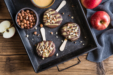Wall Mural - Apple popsicle dipped in chocolate and caramel, studded with hazelnuts