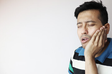 a young male holding lower chin in pain and agony due to toothache isolated in white with copy space for text.