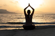 © Stockphototrends - Silhouette, young woman with protective surgical face mask performs yoga stretching exercises at the beach at dusk during covid-19 coronavirus pandemic