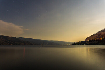 Wall Mural - starry sky seen from the shore of Okanagan lake at night with city of Penticton Canada