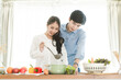 © Kris Tan - Happy Asian couple cooking together in their loft kitchen at home.