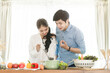 © Kris Tan - Happy Asian couple cooking together in their loft kitchen at home.
