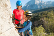 © zhukovvvlad - A woman instructs how to use a carabiner for belaying.