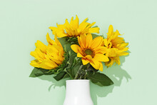 Autumn Flower Of Sunflower In White Vase On Mint Colored Background. Natural Bright Yellow Blossom With Green Leaves.