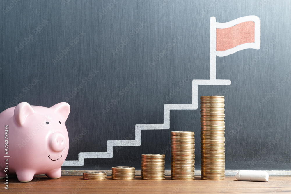 Saving money little by little with goal. Stack of coins and piggy bank. Steps and flag drawn on blackboard. - obrazy, fototapety, plakaty 