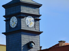 Gray Zink Clad Clock Tower. Pronounced Horizontal Seams. White Clock Face. Golden Clock Hands. Clear Blue Sky Background. Popular Tourist Attraction And Destination In The Castle District In Budapest
