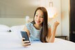 © siraphol - Portrait beautiful young asian woman use smart mobile phone on bed