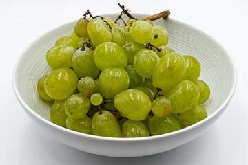 Fresh green grapes in a bowl, isolated on white background