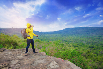 Successful male hiker with trek pole and binocular at mountain peak celebrate his freedom enjoy with nature