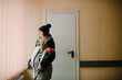 © Serhii - Pregnant woman in winter coat and warm cap in hospital. Little girl with flowers. Day of birth. Birthday.
