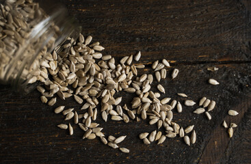 Wall Mural - Sunflower seeds scattered on the wooden vintage table from a jar.