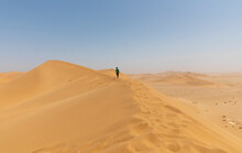 Boy Walking Along Sunny Desert Sand Dune Ridge, Namibia
