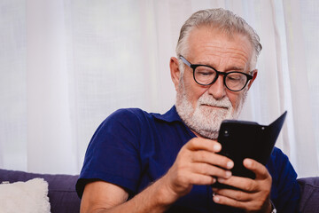 old man looking at the smartphone for reading news update or playing social network apps.