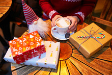 Closeup Of Woman's Hands With Cup Of Coffee And Wrapped Christmas Presents