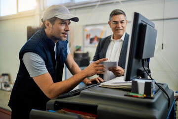 Car mechanic and his manager using computer in auto repair shop.