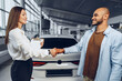 © fotofabrika - Woman car seller and man car buyer handshaking in car salon