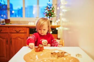 Adorable little toddler girl cooking Christmas cookies