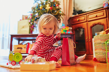 Adorable toddler girl playing with presents on Christmas morning