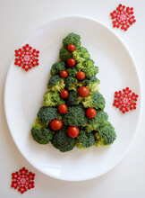 Christmas Tree Made Of Broccoli And Small Tomatoes With Red Snowflakes On White Plate On White Background. Healthy Organic Food. Festive Idea For Christmas And New Year Holidays Design.