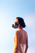 Brunette Woman In Gas Mask Standing On Blue