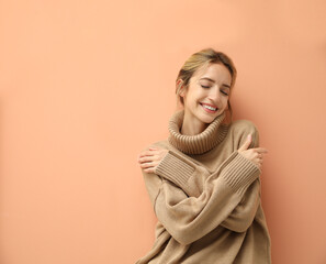 beautiful young woman wearing knitted sweater on light brown background. space for text