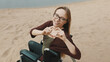 © CameraCraft - Suport for disabled people. Young woman in the wheelchair on the sandy river coast showing heart with hands. High quality photo