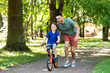 © Syda Productions - family, fatherhood and leisure concept - happy father teaching little son to ride bicycle at park