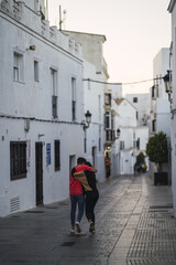 Poster - Young couple holding hands walking through white town