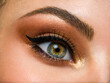 © Valua Vitaly - Beautiful female eye with brown, shiny makeup. Fashionable brown makeup. Macro image of a woman's eye.
