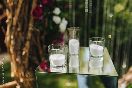 Fotografía A glass candlestick with a candle, white sand, paraffin and wax inside stands on a glass table