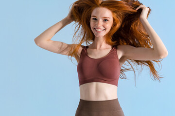 Wall Mural - Photo of redhead smiling sportswoman making fun with her hair