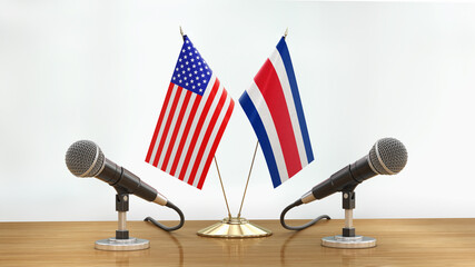 Microphones and flags pair on a desk over defocused background