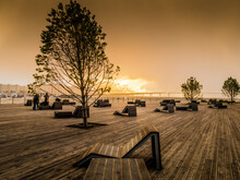 Sunset On The Neva River Wooden Embankment With Benches In Saint-Petersburg Overlooking The Bridge Across The Bay