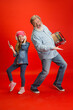 © master1305 - Music team. Senior man spending happy time with granddaughter on red background. Joyful elderly lifestyle, family, childhood, tech concept. Enjoying modern music, technologies. Copyspace.