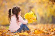 Happy Girl Playing Yellow Leaves In The Autumn Park. Beauty Nature Scene With Family Outdoor Lifestyle. Happy Girl Having Fun Outdoor. Happiness And Harmony In Childhood