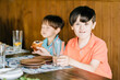 © Iryna - Two children having lunch. Smiling happy boy with down syndrome with his brother sitting together at the table.
