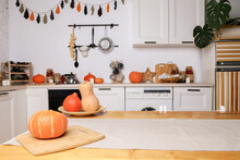 Modern Kitchen In Light Colors With Autumn Decor, Orange Pumpkins For Halloween, Handmade Garland On The Wall, Stylish Furniture And Dishes