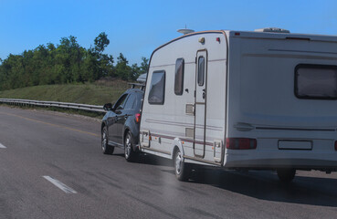 Wall Mural - SUV with a camping trailer is moving along the road