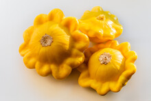 Three Yellow Ripe Squash Lie On A White Background In The Light Of The Sun