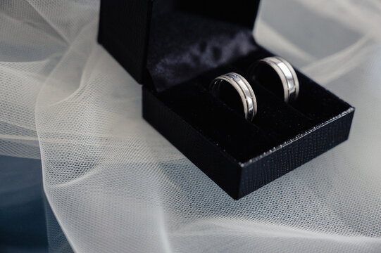 Wedding rings lie in a black heart-shaped case.