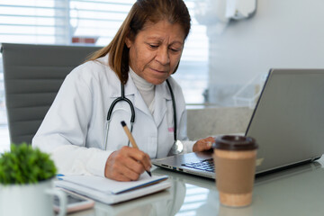 Serious senior female doctor with pen taking notes during online medical appointment in doctors office healthcare, clinic, treatment concept..