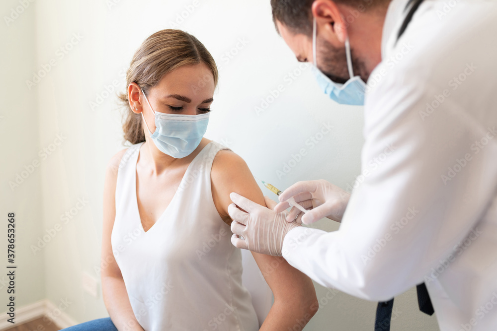 Doctor applying a vaccine on a woman's arm - obrazy, fototapety, plakaty 
