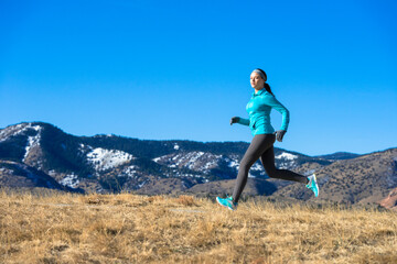 Young woman running jogging in winter with Rocky Mountains in Background