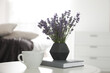 Beautiful lavender flowers, cup of coffee and book on white table indoors
