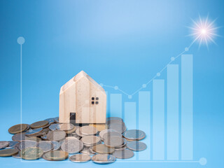 Model wooden houses and wooden dolls Stand by the pile of money With a financial graph in the foreground on a blue background.