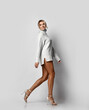 © Dmitry Lobanov - Flirty tall sexy slim long-legged blonde woman in knitted sweater and high-heeled shoes coquettishly runs away. Side view