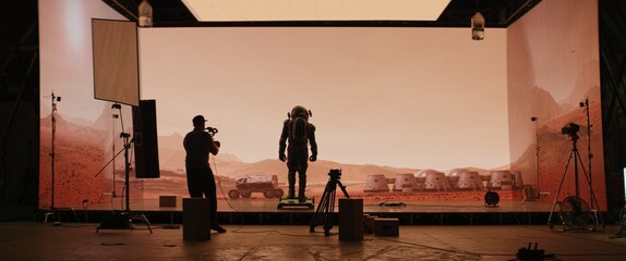 Wall Mural - Behind the scenes shot of virtual production stage with huge LED screens, cinematorgapher shooting Mars scene. Future of movie production